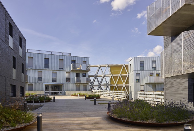 Deux des trois volumes sont reliés par une passerelle aérienne offrant un espace ouvert sur le paysage. De généreux balcons en saillie rythment les façades.<br/> Crédit photo : CHALMEAU Stéphane