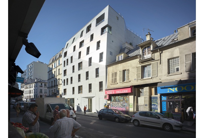 Côté rue, le volume homogène de la façade se déplie en trois plans, pour créer le lien avec les gabarits voisins et ainsi marquer une continuité entre la maison en R+1+C et l'immeuble en R+4+C. <br/> Crédit photo : LANOO Julien